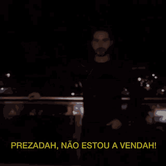 a man with a beard says " prezadah " in a dark room