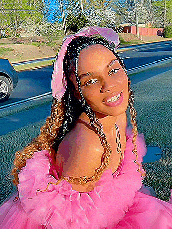 a woman wearing a pink dress and a pink headband is smiling .