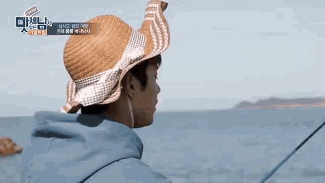 a man in a straw hat is fishing in the ocean .