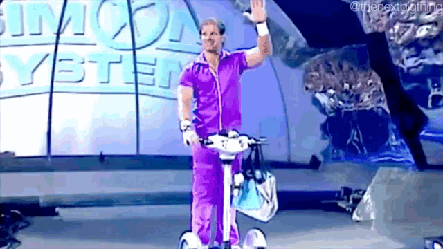 a man in purple pants is riding a scooter on a stage