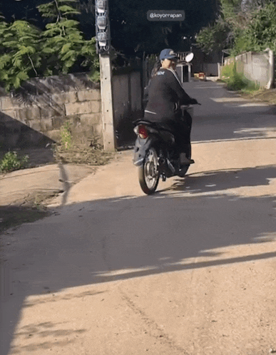 a person riding a motorcycle down a dirt road with a sign above them that says koyorrapan
