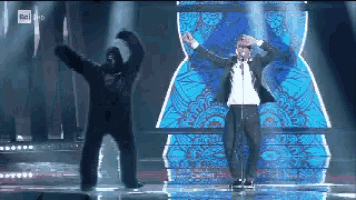 a man in a suit stands next to a gorilla on a stage in front of a sign that says rai hd