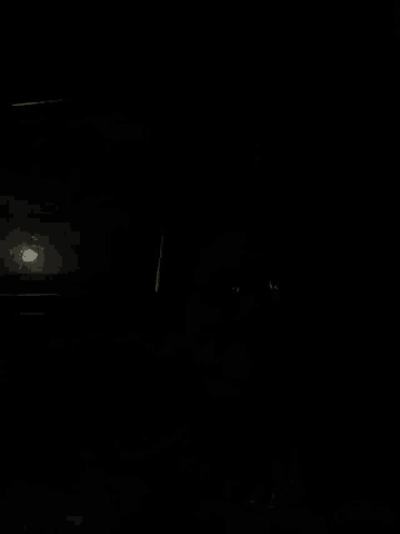 a person is sleeping in a dark room with a picture of a ghost in the background .