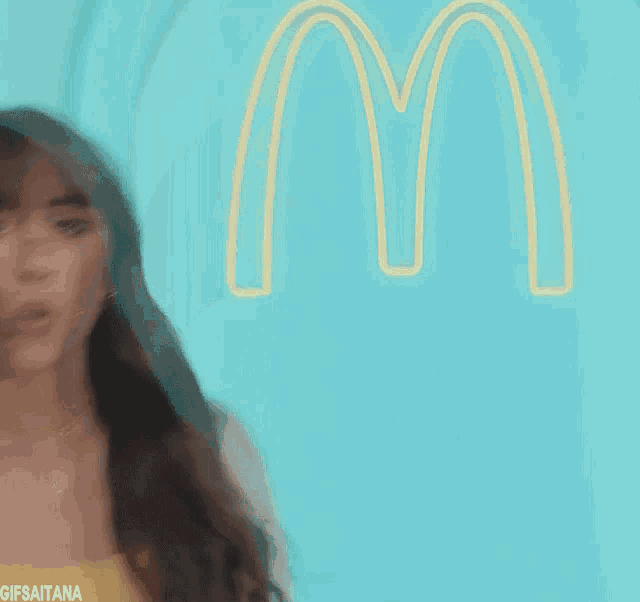 a woman is standing in front of a mcdonald 's logo
