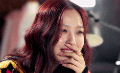 a woman with red hair is smiling and covering her mouth