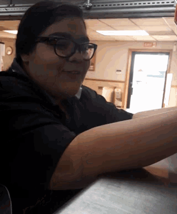 a woman wearing glasses is sitting at a counter in a restaurant
