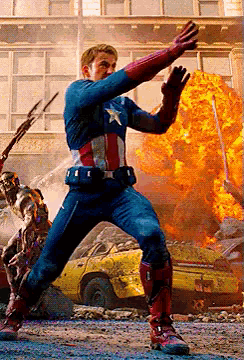 a man in a captain america costume is standing in front of a building with a car in the background