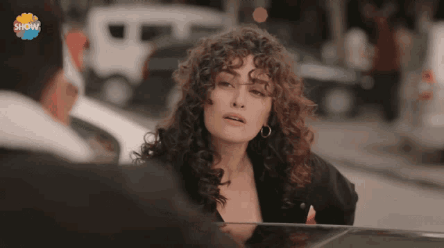 a woman with curly hair is standing next to a man with the word show on the bottom right