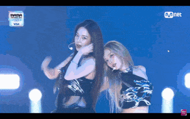 two women are dancing on a stage with a visa logo in the background