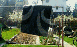 a black and white rug is hanging on a clothesline in a yard