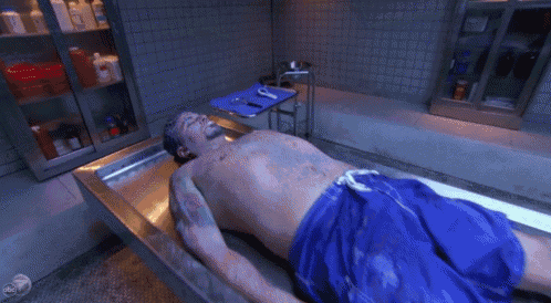 a shirtless man in blue shorts is laying in a morgue