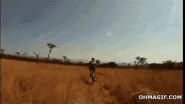 a man is riding a bike in a field with the website ohmagif.com visible