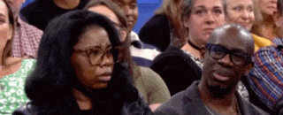 a man and a woman are sitting in a crowd of people on a television show .