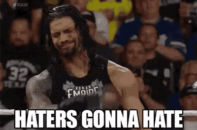 roman reigns is standing in front of a crowd and saying `` haters gonna hate '' while wearing a black tank top .
