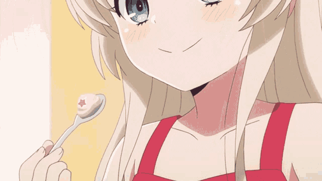 a girl in a red top is holding a spoon in her mouth