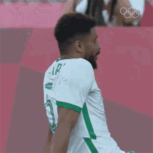 a man with a beard is wearing a green and white soccer jersey with the number 6 on it .
