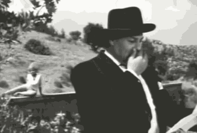 a man in a cowboy hat is smoking a cigarette in a black and white photo
