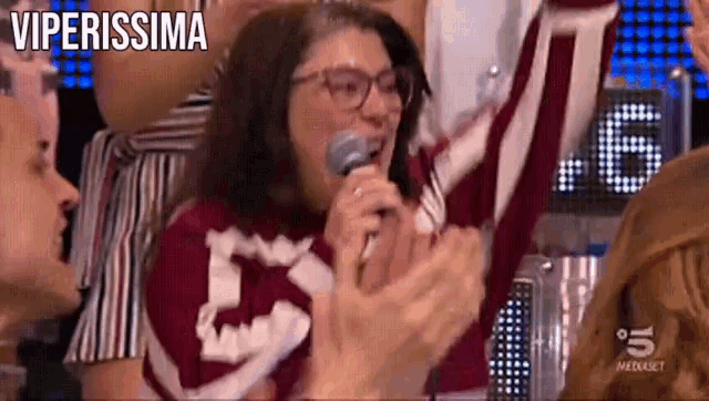 a woman holds a microphone in front of a crowd and the word viperissima is above her