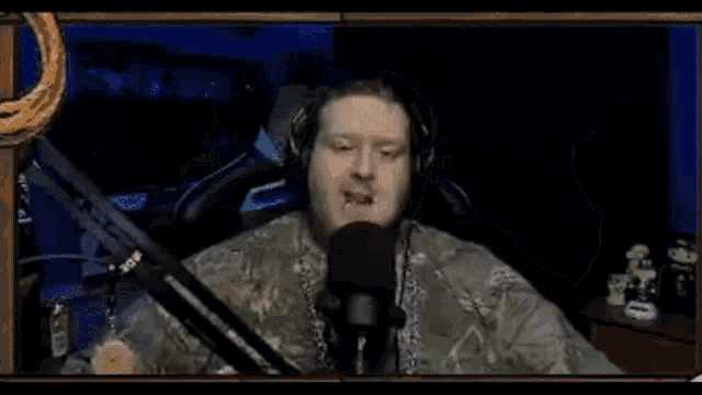 a man wearing headphones is sitting in front of a microphone with his arms outstretched .