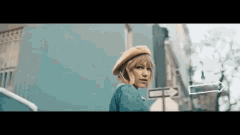 a woman wearing a beret and a blue jacket is walking down a city street .