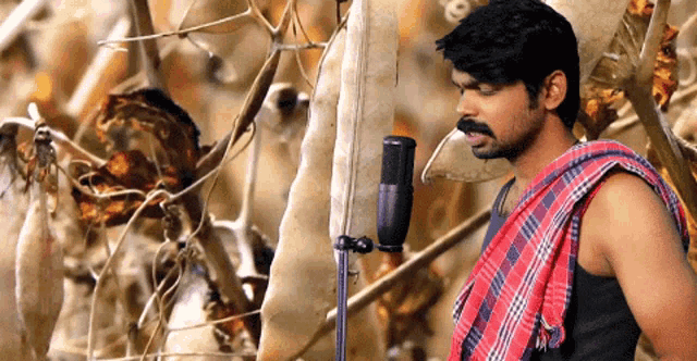 a man with a mustache is singing into a microphone in a field