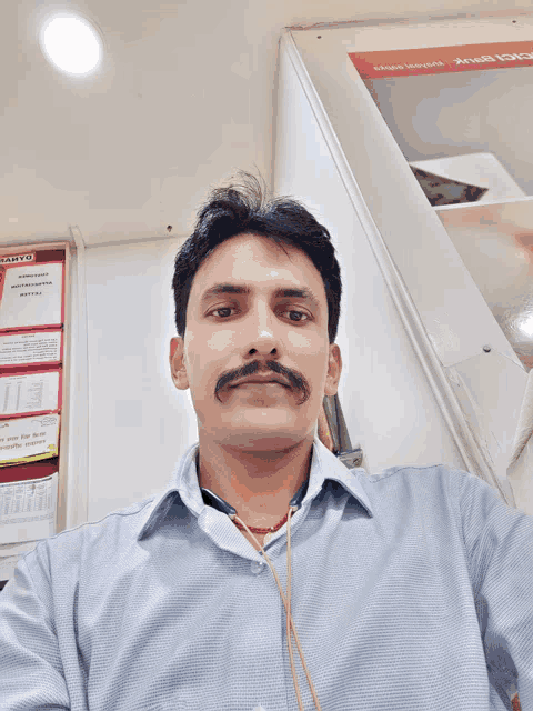 a man with a mustache is taking a selfie in front of a wall that says sanyo