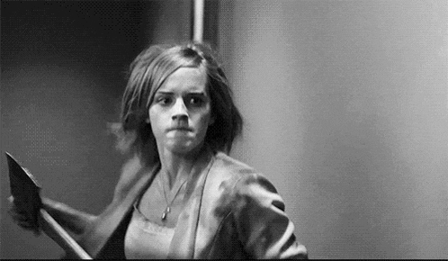 a black and white photo of a woman holding a knife and looking at the camera .