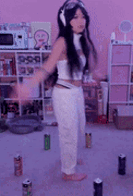 a woman wearing headphones and goggles is standing in a room surrounded by cans of soda