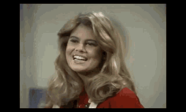 a woman with blonde hair is smiling and wearing a red jacket .