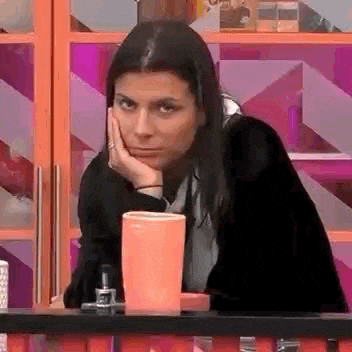 a woman is sitting at a table with her hand on her chin and a cup in front of her .