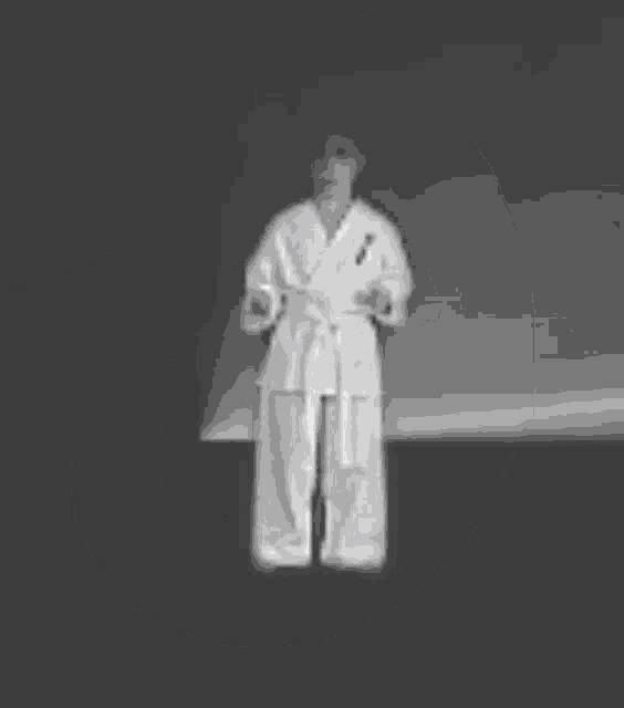 a black and white photo of a person in a karate uniform standing in front of a crescent moon .