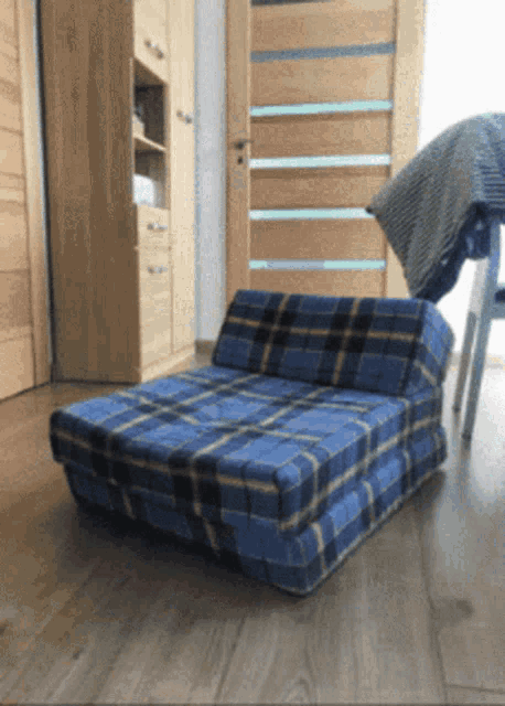 a blue plaid ottoman sits on a wooden floor in a room