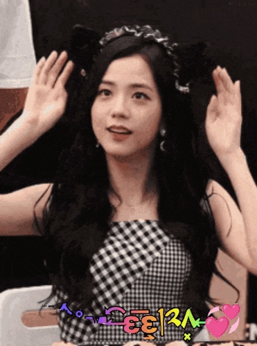 a girl wearing a cat ear headband is waving her hand