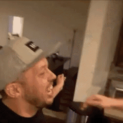 a man wearing a hat is being punched in the face by another man .