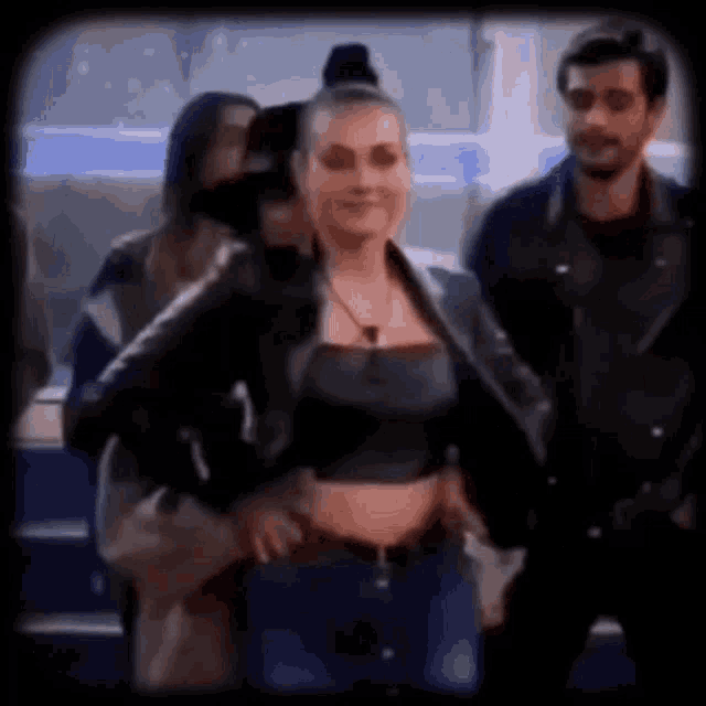 a woman in a crop top and a leather jacket is standing next to a man in a leather jacket .