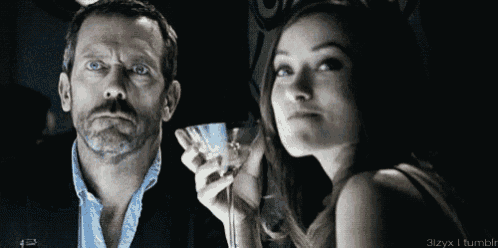 a man holds a martini glass next to a woman who is looking at him