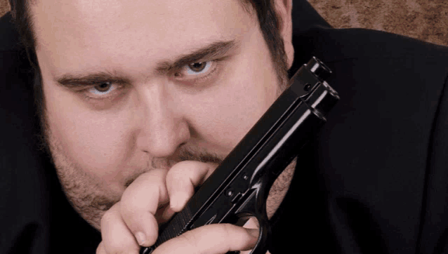 a man with a beard holds a gun to his face