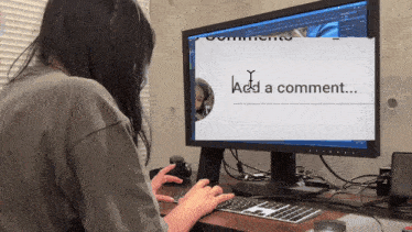a woman is typing on a keyboard in front of a computer screen which says add a comment