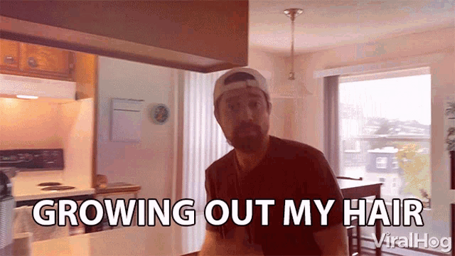 a man in a kitchen with the words growing out my hair behind him