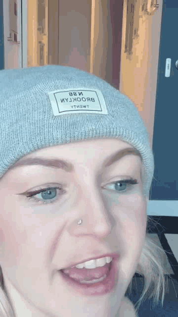 a woman wearing a gray beanie with a white label that says " 88 и " on it