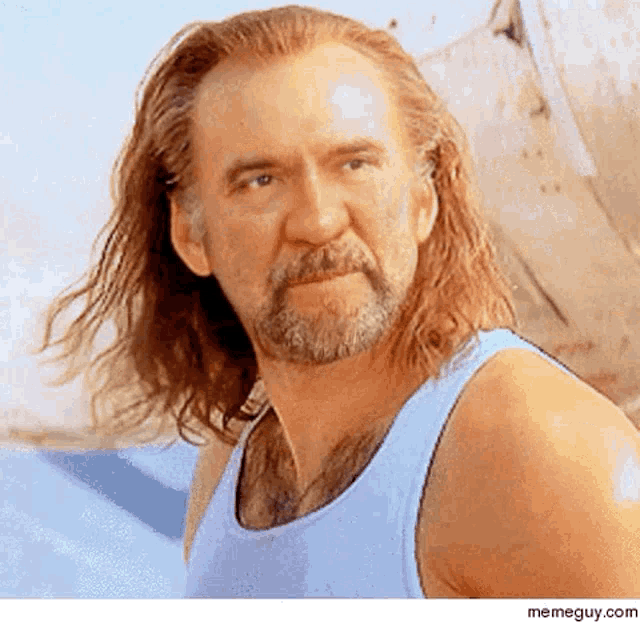 a man with long hair and a beard in a blue tank top
