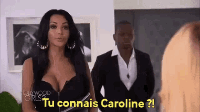 a woman in a black dress is standing next to a man in a suit and says `` tu connais caroline '' .