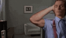 a man wearing a blue shirt and red suspenders is covering his ears with his hands .