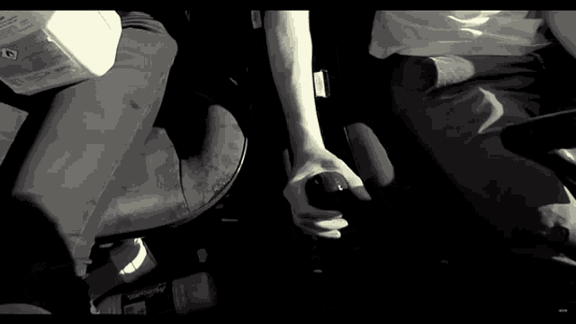 a black and white photo of a person 's hand holding a bottle