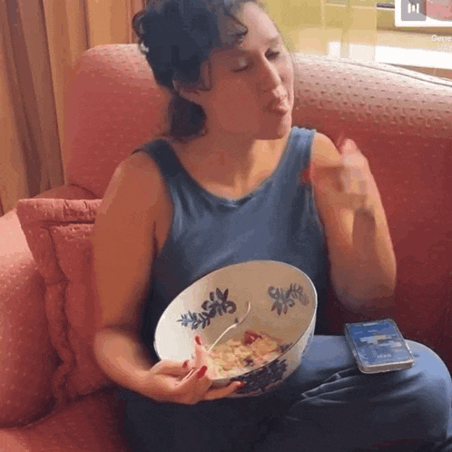 a woman sitting on a couch with a bowl of cereal