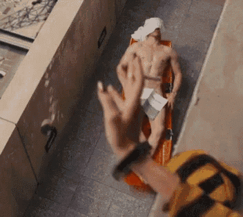 a shirtless man is laying on a stretcher with a towel on his head