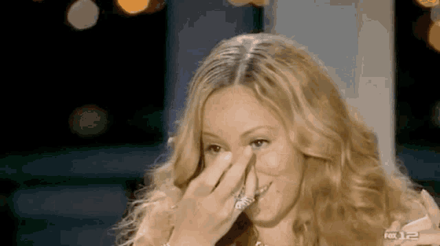 a woman is covering her face with her hand .