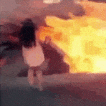 a blurry picture of a girl standing in front of a fire .
