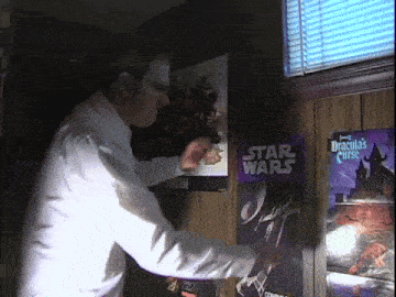 a man is standing in front of a star wars poster and dracula 's curse poster
