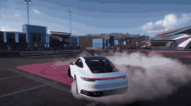 a white porsche is drifting on a track with smoke coming out of it